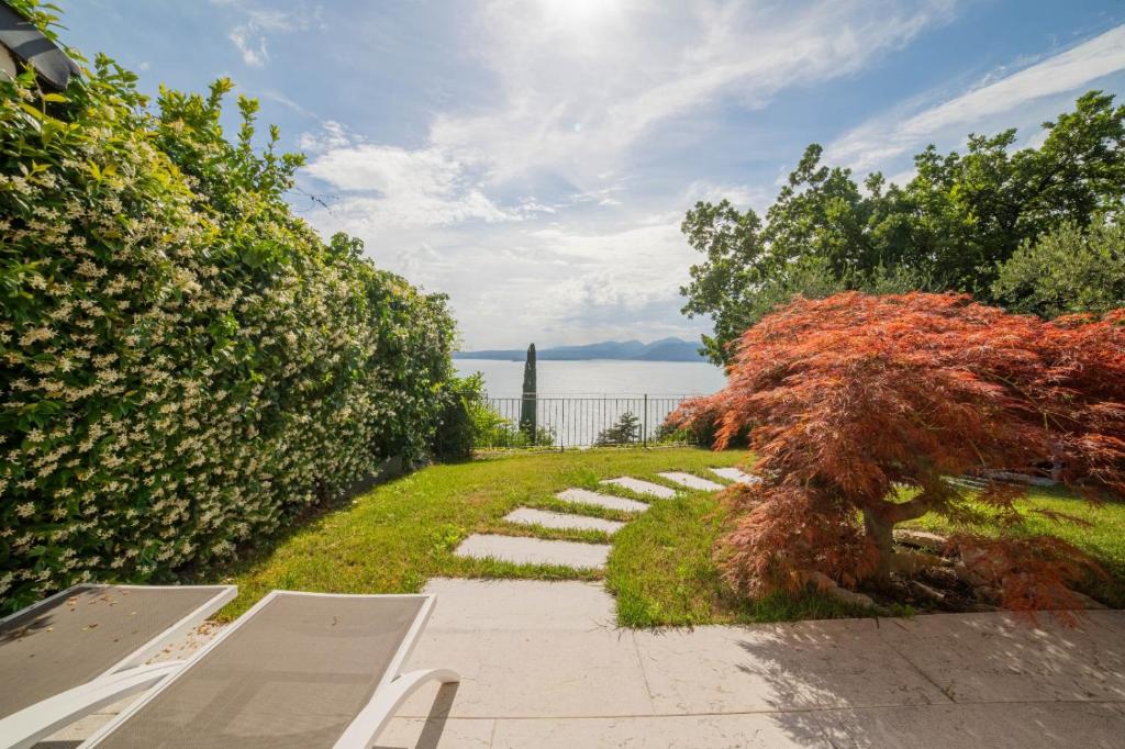 a pathway leading to a garden with a tree at Robur Gardae Panoramic Suite in Torri del Benaco
