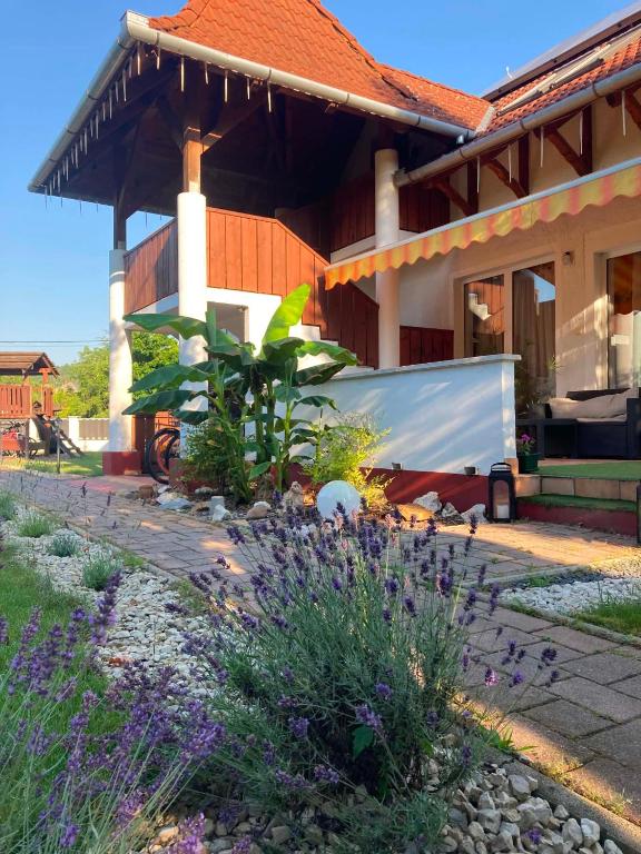 a house with a garden with purple flowers in front of it at Napsütötte Kehida in Kehidakustány