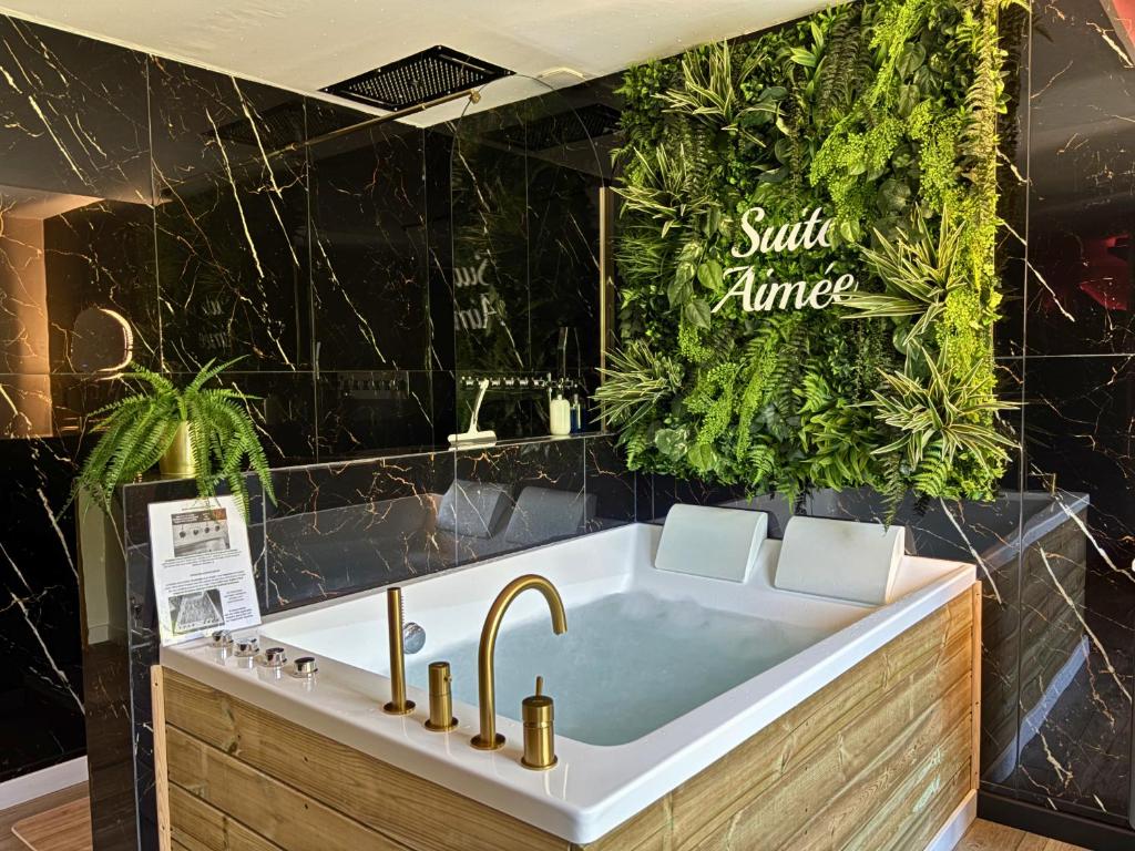a bath tub with a sink in a bathroom at La Suite Aimée - Espace relaxant avec balnéo in Angoulême