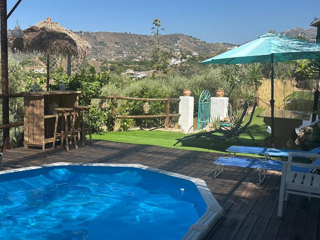 a pool on a deck with a table and an umbrella at La Casa Turquesa in Frigiliana
