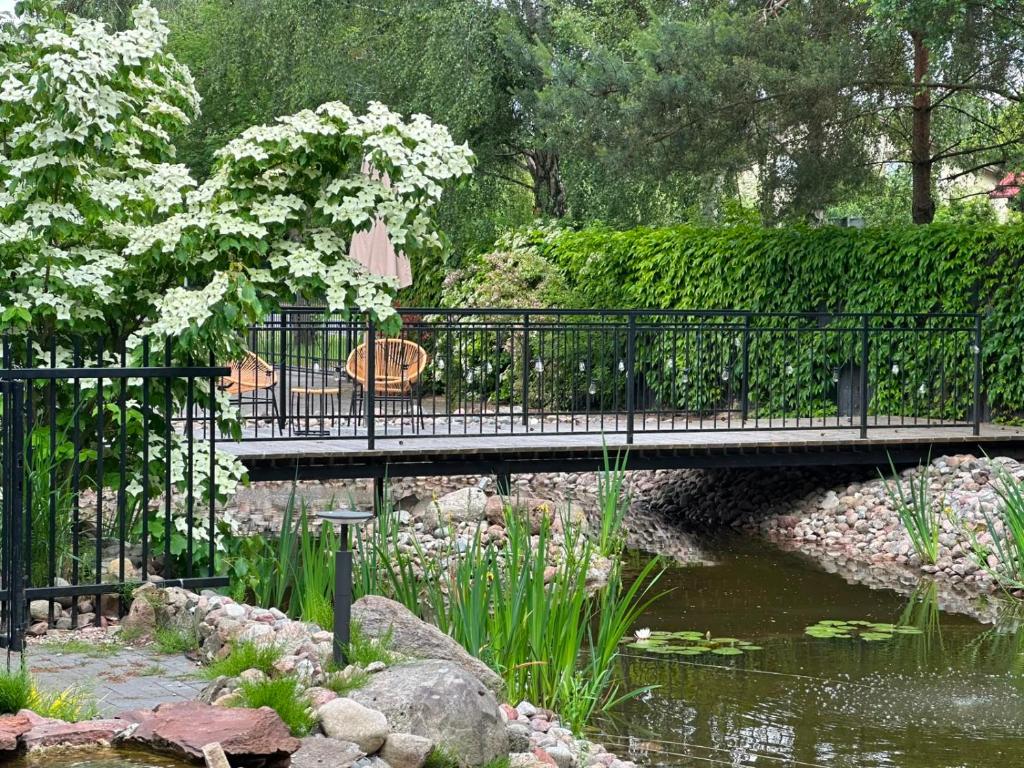 a bridge over a pond with a bench and flowers at Apartamenty Terminal Charzykowy in Charzykowy