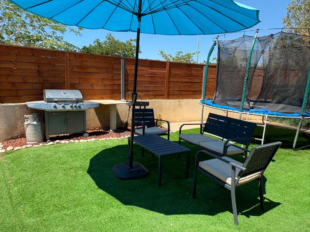 a patio with two chairs and an umbrella and a grill at Rest&breath in Nir Yafe