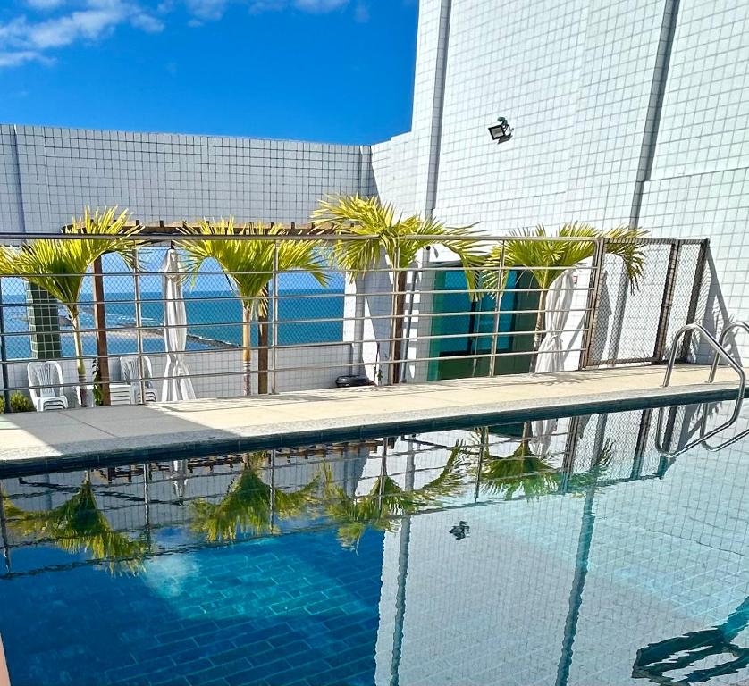 a swimming pool with palm trees in front of a building at Summer house in Olinda