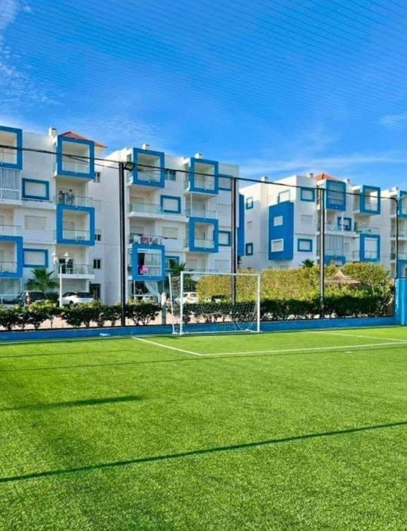 a tennis court in front of a large apartment building at Alta-Home cabo in Cabo Negro