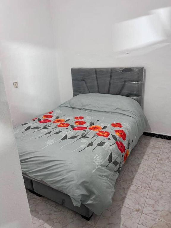 a bed with red flowers on it in a bedroom at Meknès,hameriya in Meknès