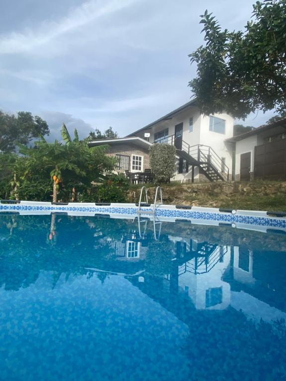 a swimming pool with blue water in front of a house at La bendición de sunnyvale cabaña pequeña 4 personas in La Vega