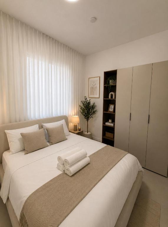 a bedroom with a large white bed with a bow on it at סוויטות אקווה איירפורט בוטיק & גרדן - By SEAELO in Eilat