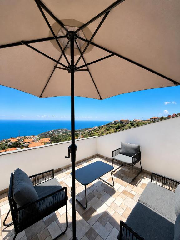 a patio with a table and chairs and an umbrella at Vista Sol in Bicas