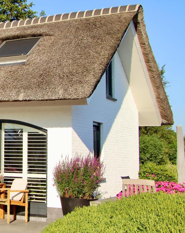 a white house with a table and a chair at Aan de Amstel in De Hoef