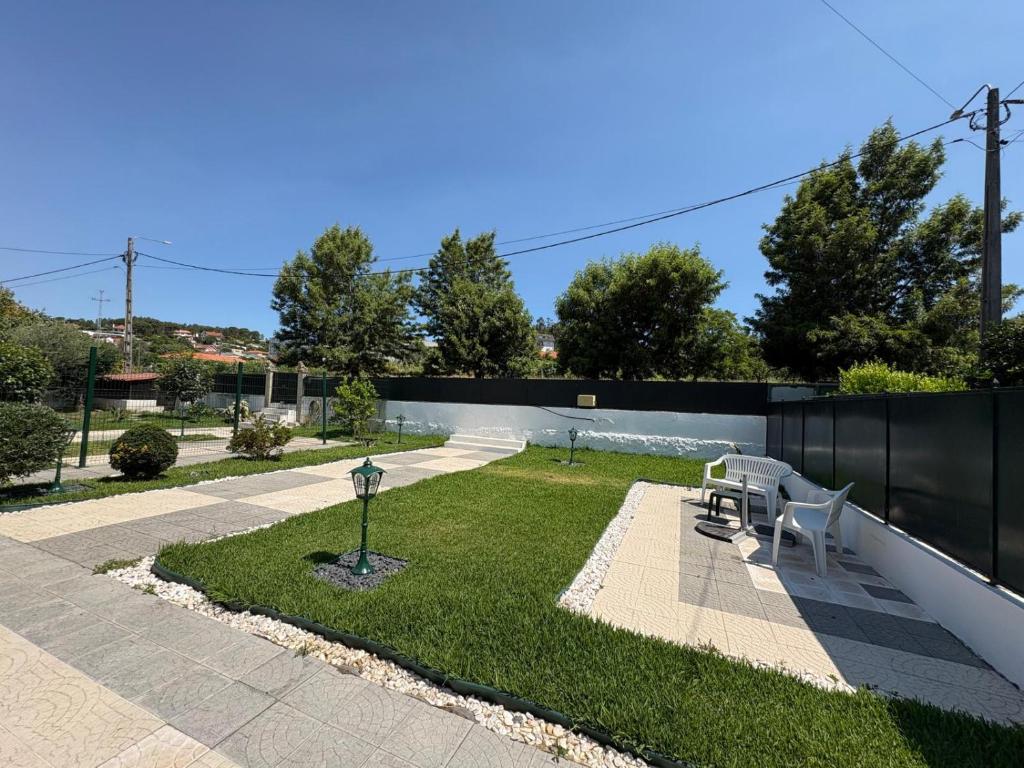 a garden with two white chairs and a fence at Casa da Pontelha VILLA INN in Ponte de Lima
