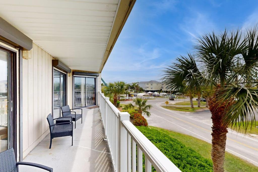 a porch with chairs and a palm tree and a street at Bay Creek Villa - 202 in Edisto Beach