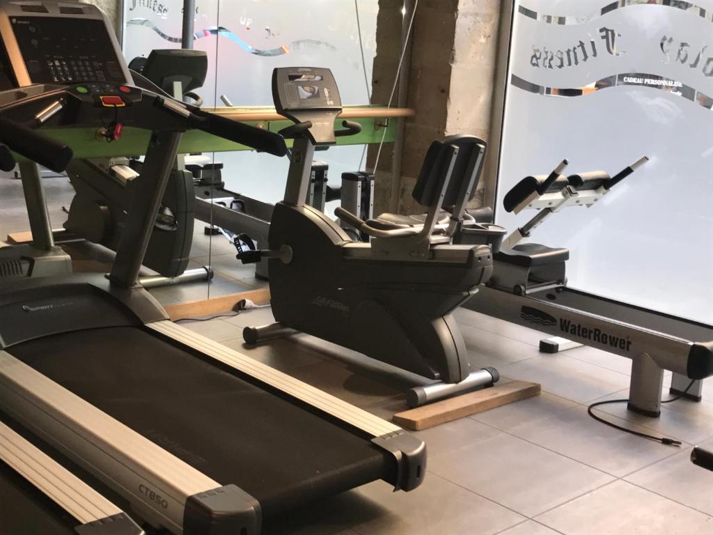 a gym with a treadmill and a laptop on a table at Hôtel Jacques De Molay in Paris