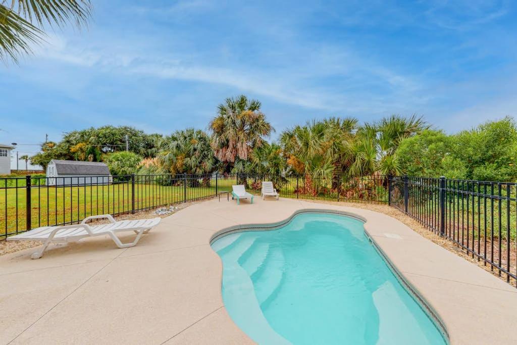 a swimming pool with two chairs and a fence at Hamptons South in Edisto Beach