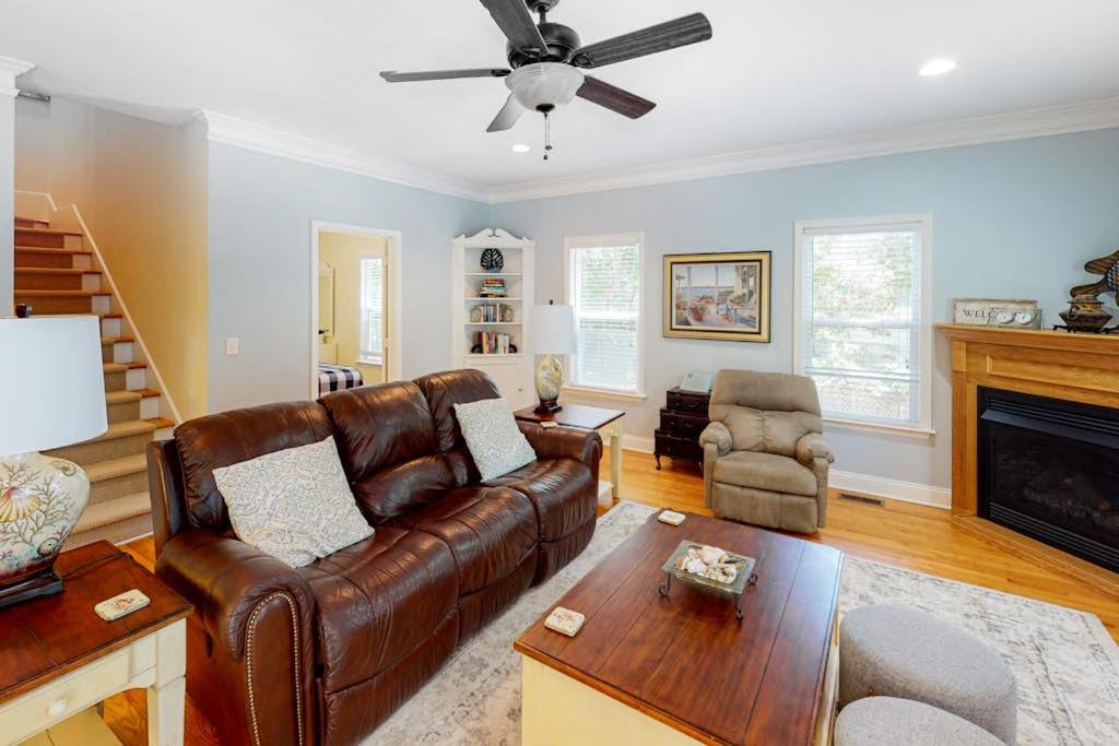 a living room with a leather couch and a fireplace at Chateau Relaxo in Edisto Beach