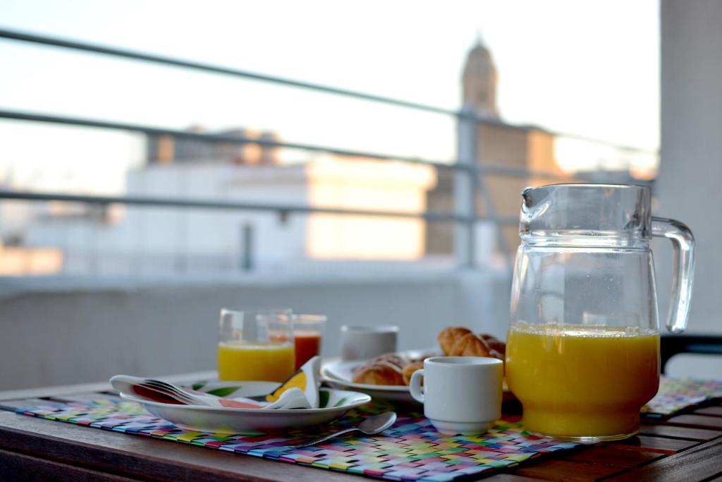 una jarra de cristal de zumo de naranja y un plato de comida en Ático con terraza y vistas, en Málaga