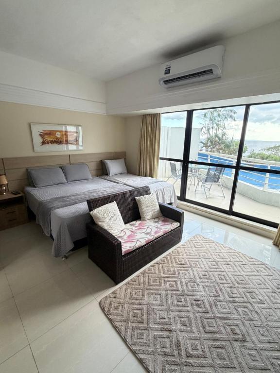 a bedroom with a bed and a couch and a window at Hotel tropical Manaus suite luxo in Manaus