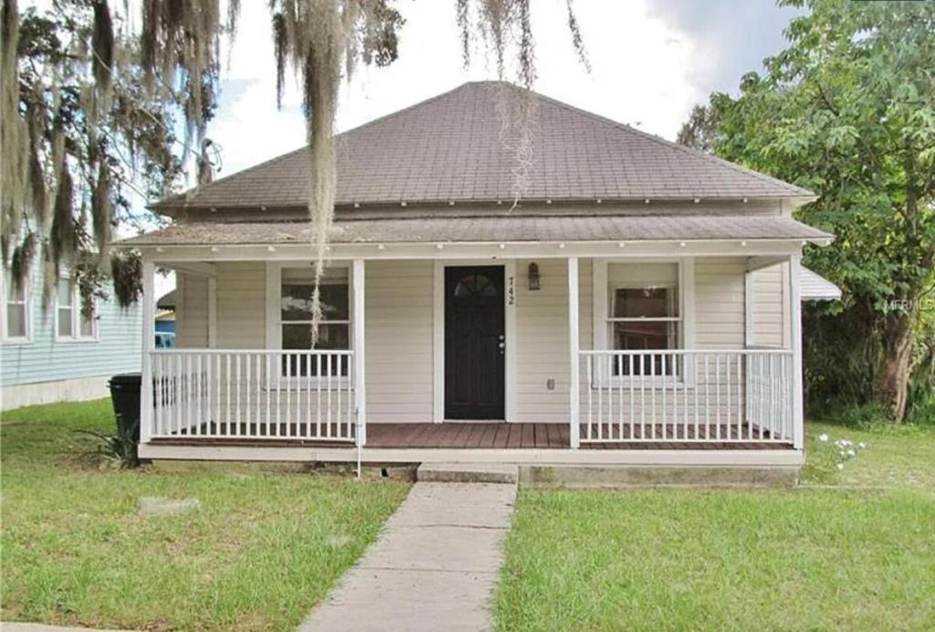 a small white house with a porch and a black door at New Haven 5 mi from Legoland in Winter Haven