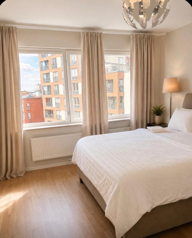 a bedroom with a white bed and two windows at Nordhaven Sundbyberg in Sundbyberg