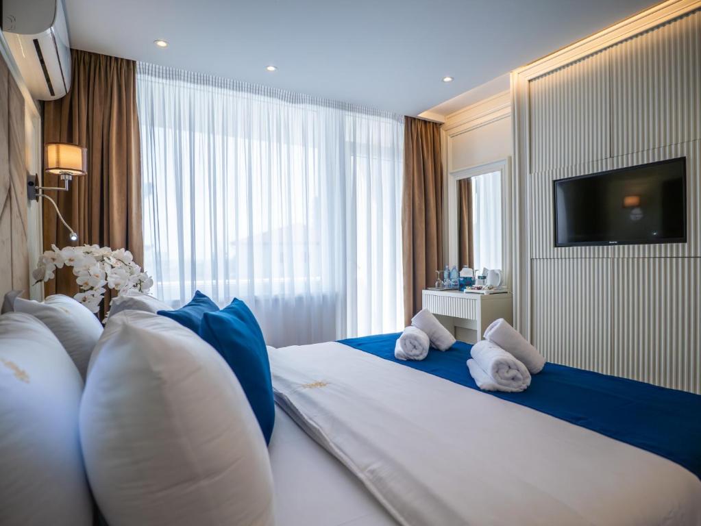 a hotel room with a large bed with blue and white pillows at Hotel Belvedere in Eforie Nord