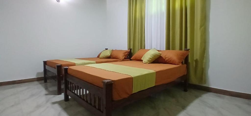 two beds in a room with green curtains at Samadi hotel and resort in Kekirawa