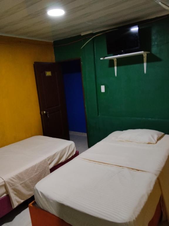 two beds in a room with a green wall at Hospedaje Mundial in Villeta