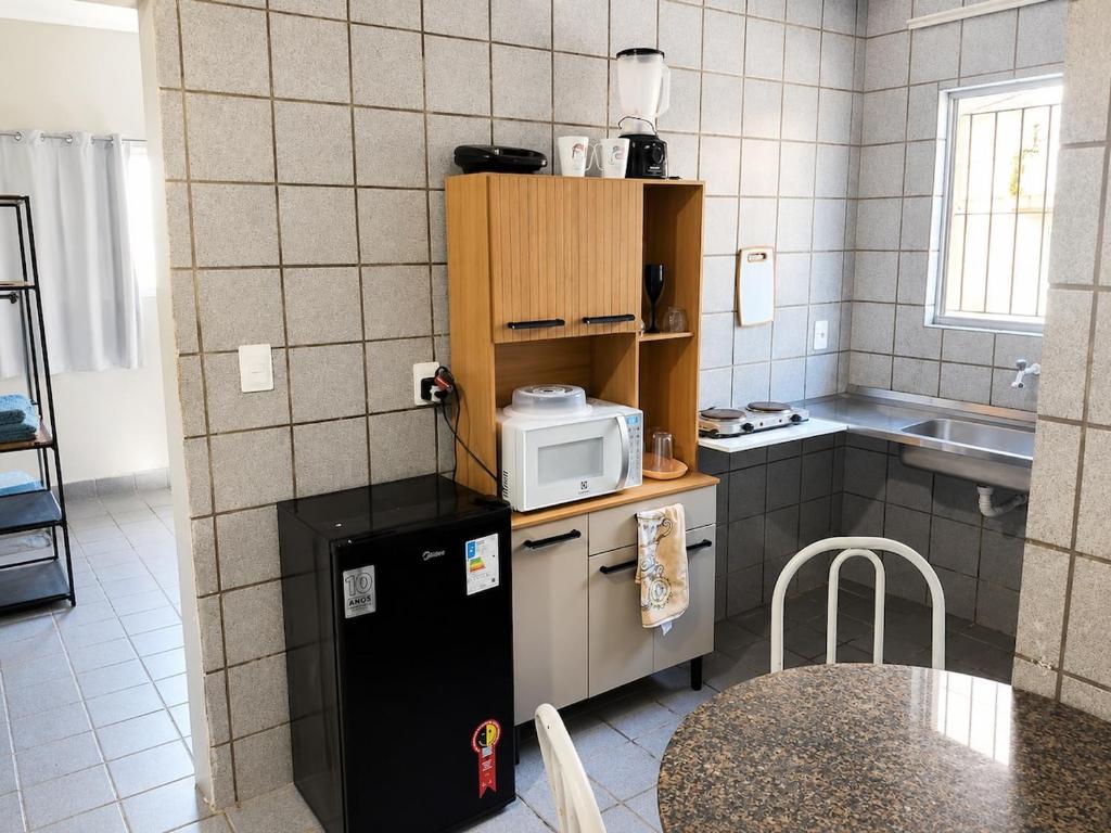 a small kitchen with a small refrigerator and a table at Studio aconchegante perto dos eventos! in Garanhuns