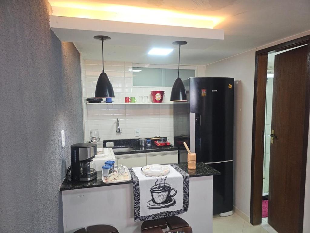 a kitchen with a counter and a black refrigerator at Suite aconchegante e Charmosa - centro de Teresópolis in Teresópolis