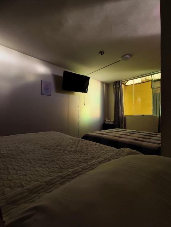a hotel room with two beds and a flat screen tv at Deluxe Miraflores in Miraflores