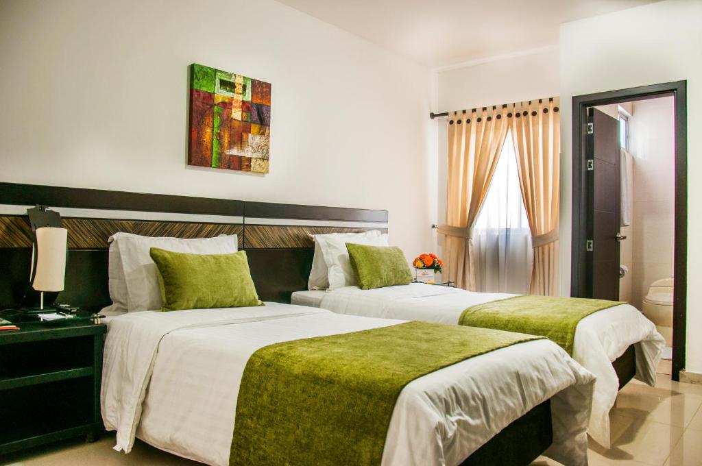 a hotel room with two beds with green sheets at Hotel San José Plaza in Bucaramanga