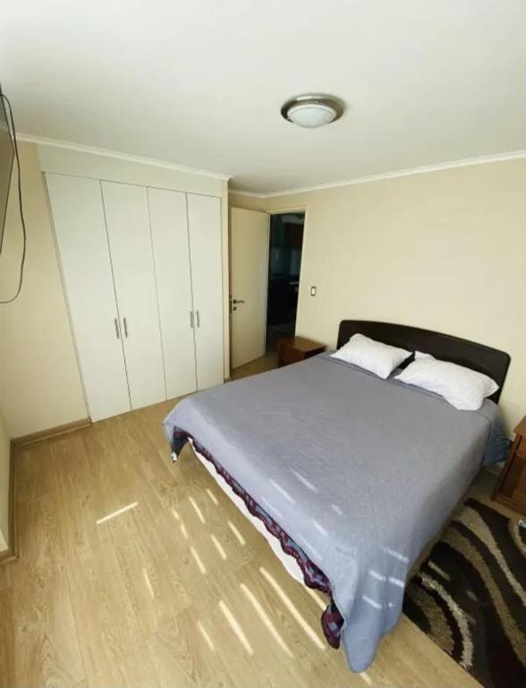 a bedroom with a large bed with white cabinets at Departamento Centro Chillán in Chillán