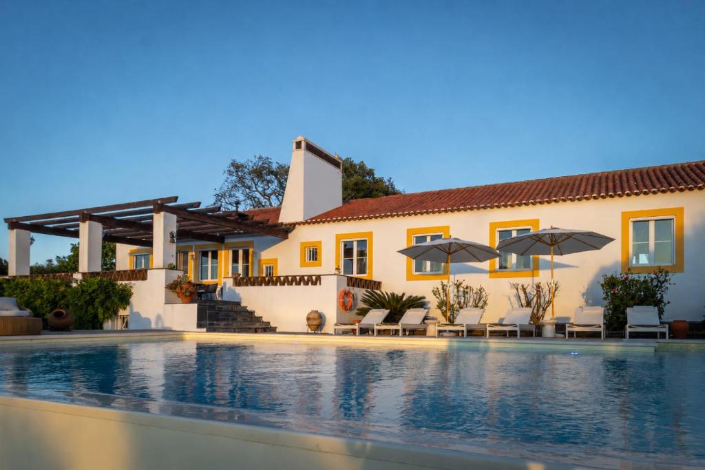 a villa with a swimming pool in front of a house at Monte da Casa Telhada in Santiago do Cacém