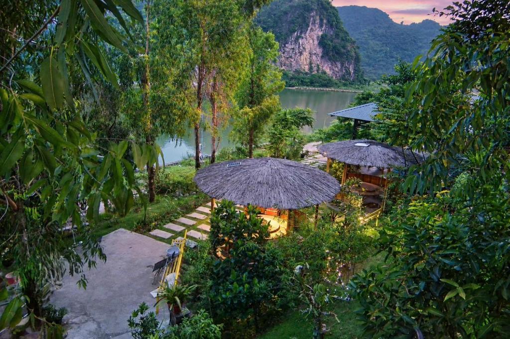 an outdoor area with umbrellas and chairs and a lake at Kingfisher Nest in Hai Phong