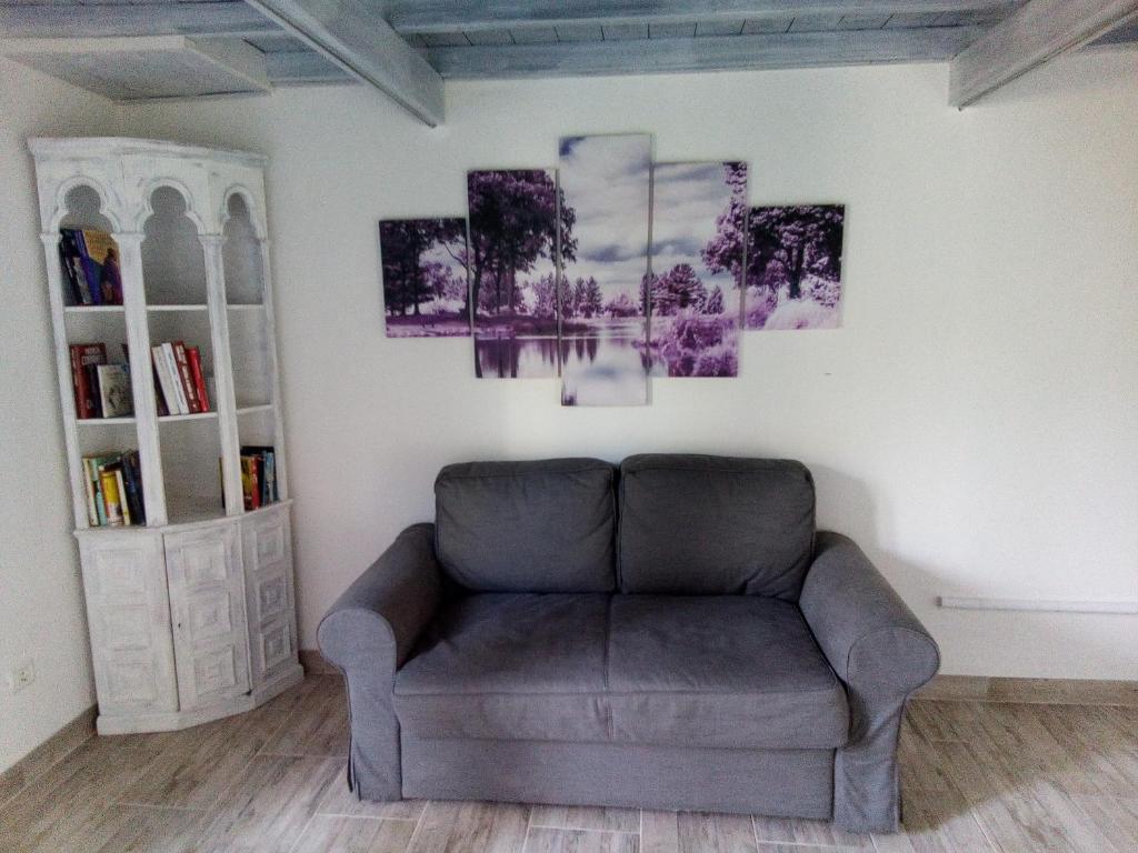 a living room with a couch and paintings on the wall at Appartamento Scirocco in Marina di Campo