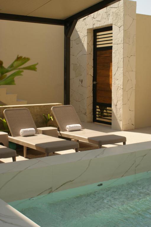 a pool with lounge chairs next to a swimming pool at Hotel Boutique Kasa Sara in San Patricio Melaque