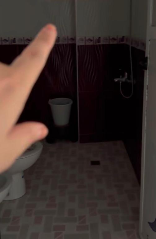 a persons hand is pointing at a toilet in a bathroom at Casa de nordin in Fnidek