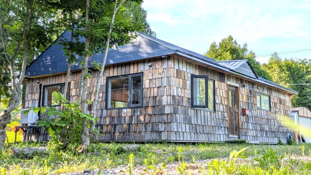 a small wooden house with a black roof at 暮らす宿ソラプチ Sorapchi Cabin in Ochiai