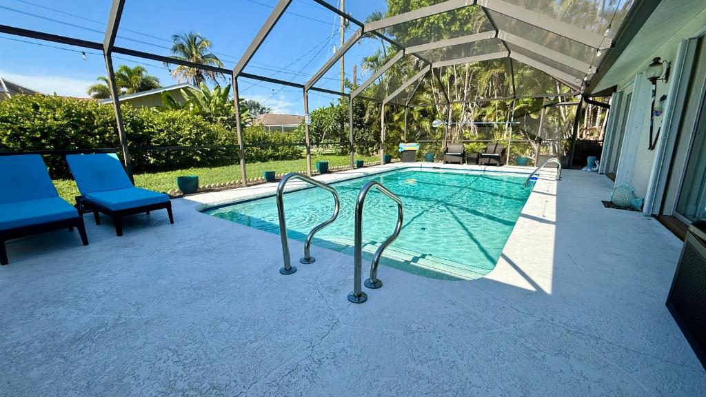 a swimming pool with two blue chairs next to a house at Relaxing place with pool in Cape Coral