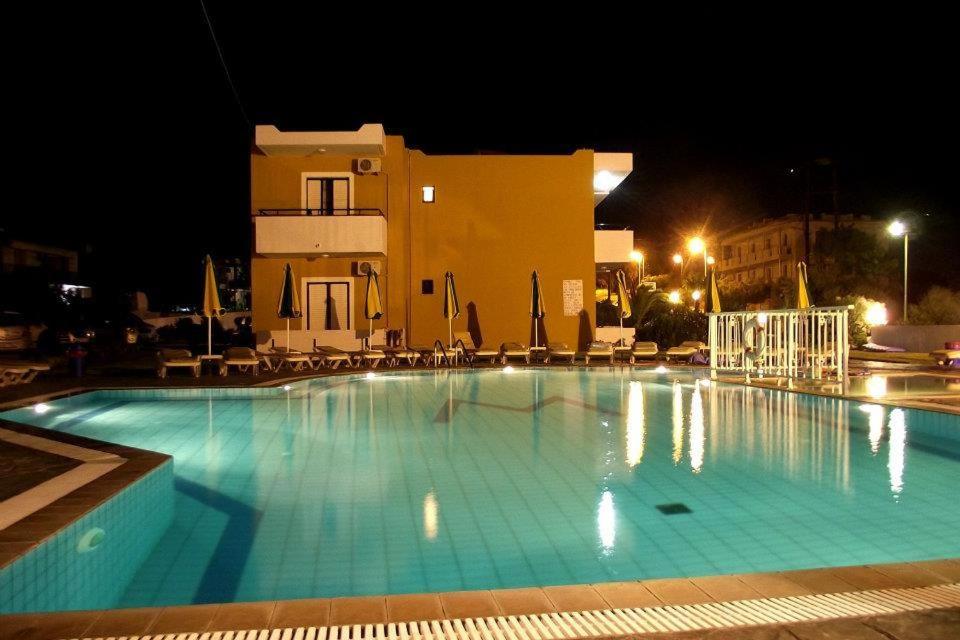 a large swimming pool in front of a building at night at Manolis Studios in Kefalos