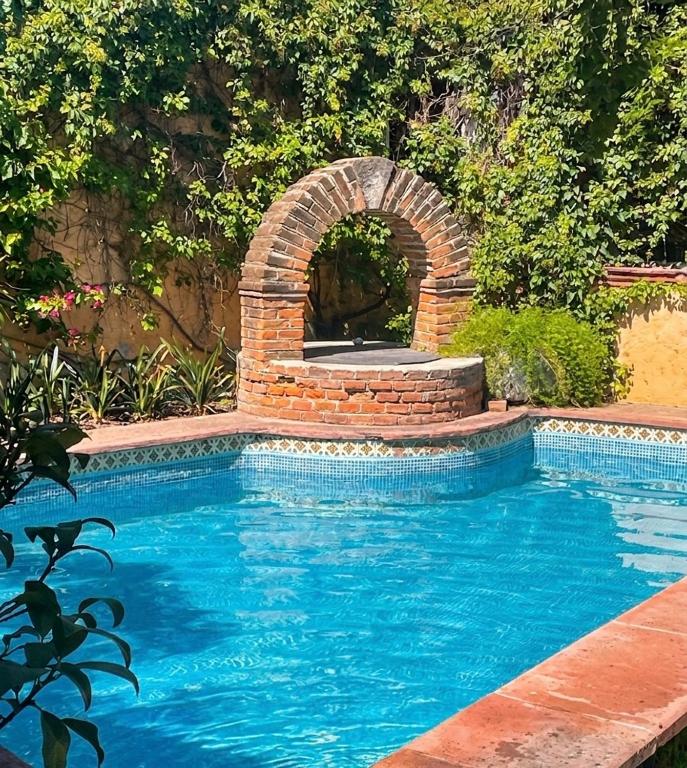 a swimming pool with a brick fountain in a yard at Casa Cantera in Tequisquiapan