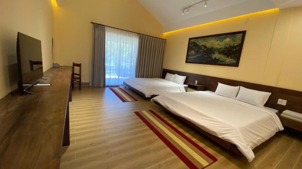 a hotel room with two beds and a television at Con Nho RiverHouse Hue in Thôn Tiên Nộn