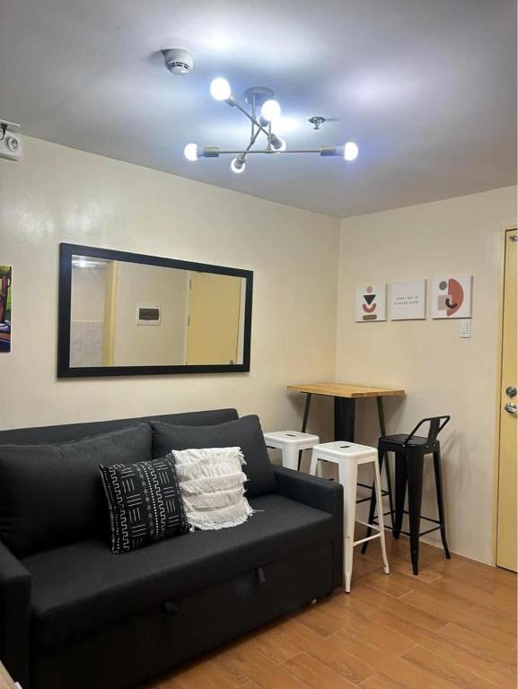 a living room with a black couch and a mirror at Davao Cozy Condo T6 unit 2 in Davao City