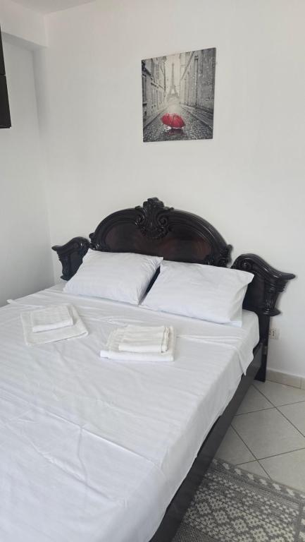 a white bed with a wooden headboard and white pillows at Maritimo Apartment in Constanţa