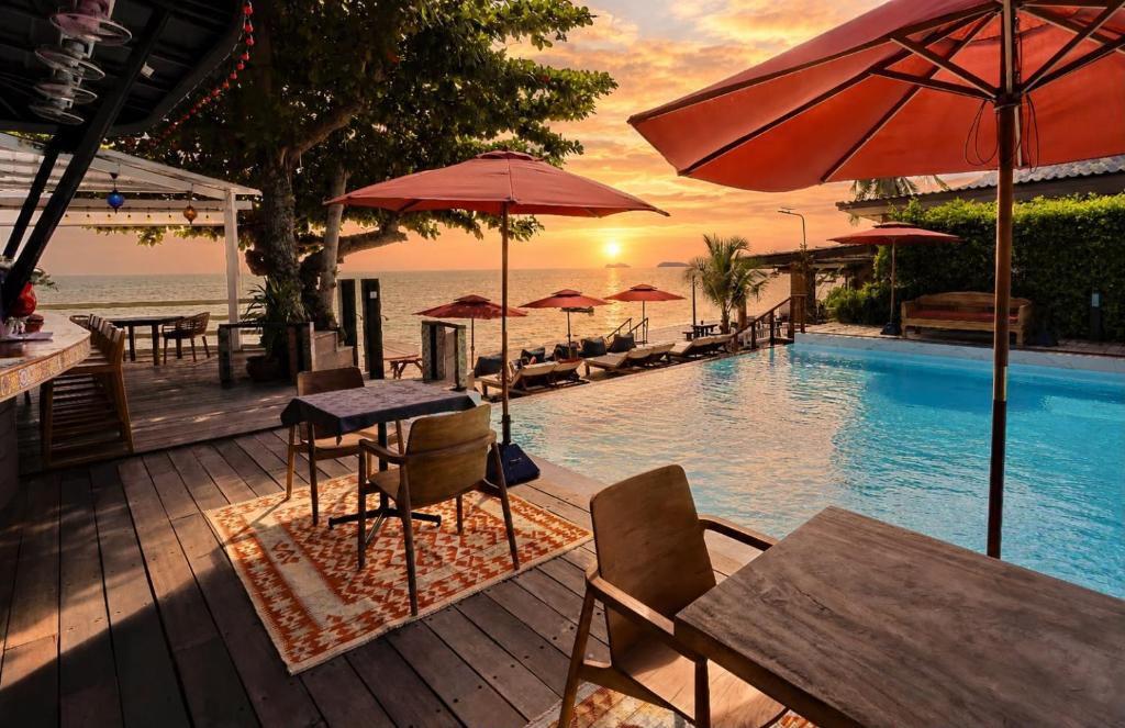 a swimming pool with tables and chairs and umbrellas at Sunset Beach Hotel - Adults Only in Haad Rin