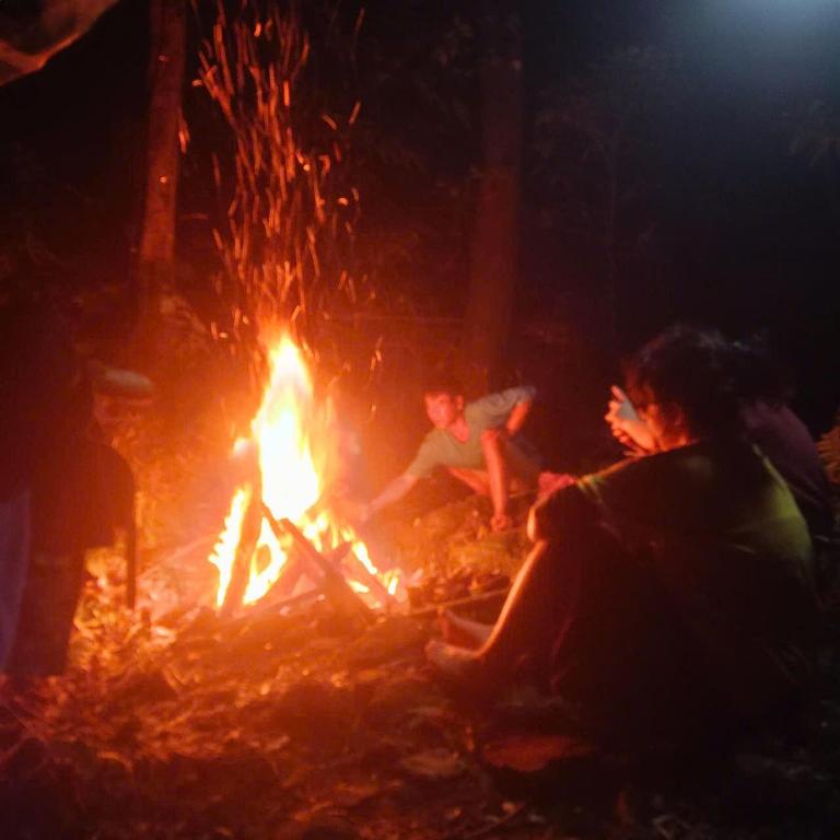 two people sitting around a fire at night at Aluoi Homestay in Hue