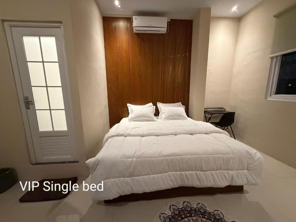 a bedroom with a large white bed and a window at Gassania Hostel in Banda Aceh