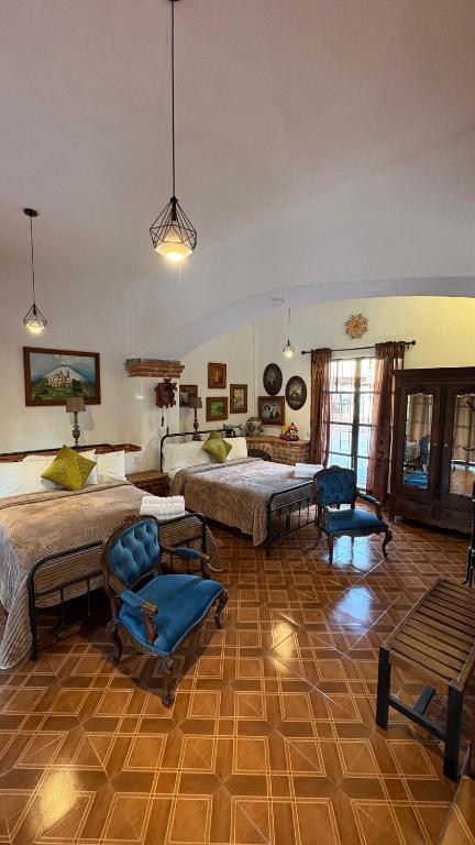 a bedroom with two beds and two chairs at Master suite en Teotihuacan in San Sebastian Xolalpa