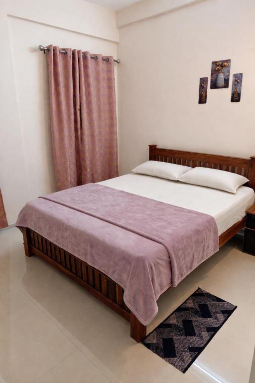 a bedroom with a bed and a red curtain at Harichandhanam stay in Guruvāyūr