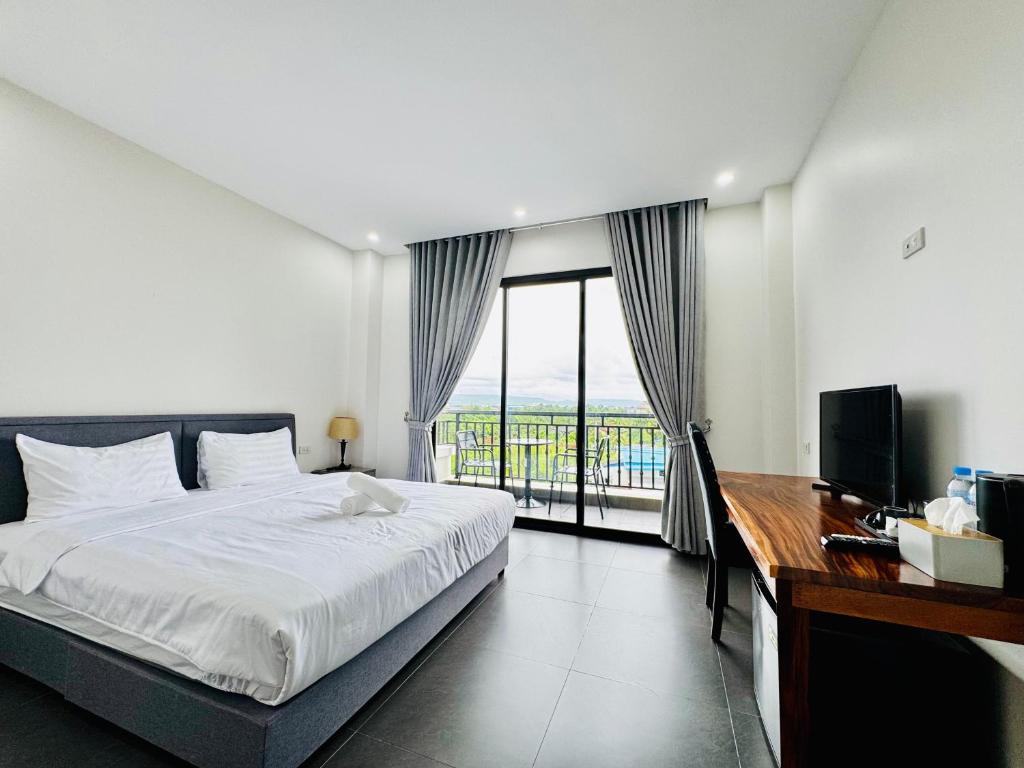 a bedroom with a bed and a desk and a window at De Zee Hotel in Koh Kong