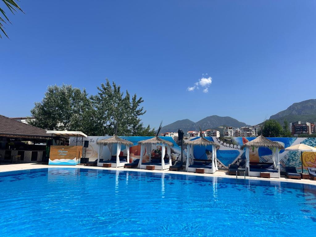 a large swimming pool with umbrellas and chairs at Chateau Linza Resort in Tirana