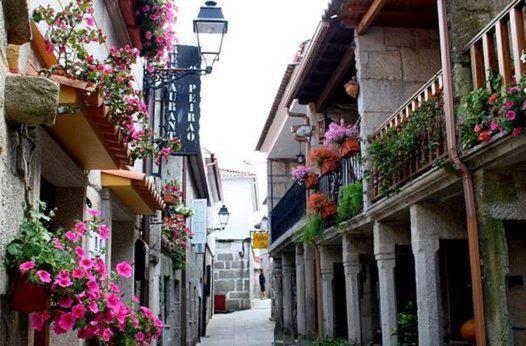 un callejón con flores al lado de los edificios en Casa Da Chousa, en Combarro